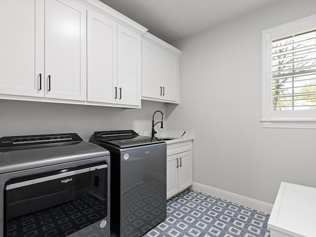 washroom with cabinets, washer and clothes dryer, and sink