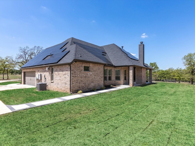 view of side of home with a garage, a lawn, and solar panels