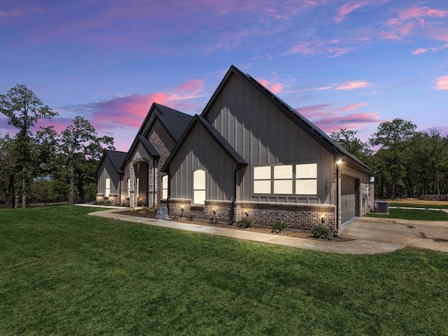 property exterior at dusk with a garage, a lawn, and central AC