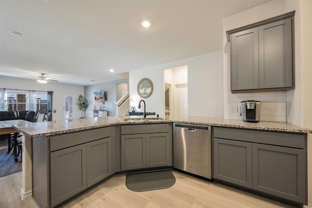 kitchen with sink, light stone countertops, stainless steel dishwasher, and gray cabinets