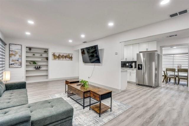 living room with built in shelves and light hardwood / wood-style floors