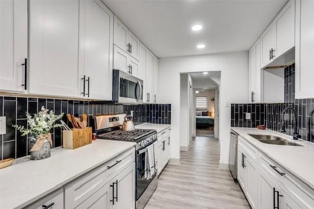 kitchen with sink, white cabinets, tasteful backsplash, and stainless steel appliances