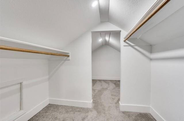 spacious closet featuring light colored carpet and lofted ceiling