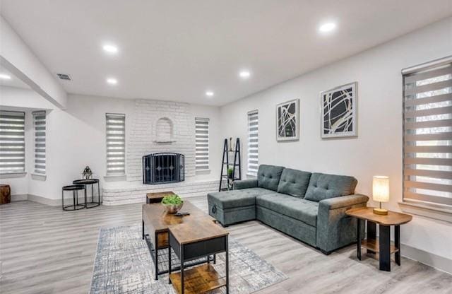 living room with light wood-type flooring and a brick fireplace