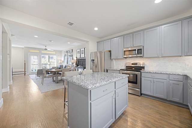 kitchen featuring stainless steel appliances, a kitchen island, gray cabinetry, and backsplash