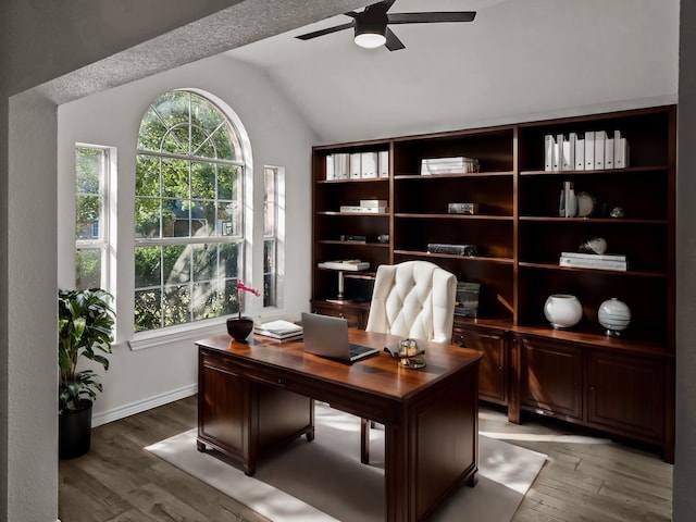 home office with ceiling fan, light hardwood / wood-style flooring, and lofted ceiling