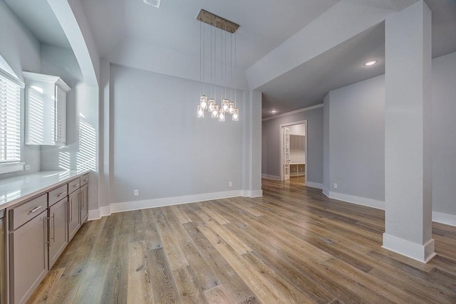 unfurnished dining area with light wood-type flooring, a chandelier, and ornamental molding