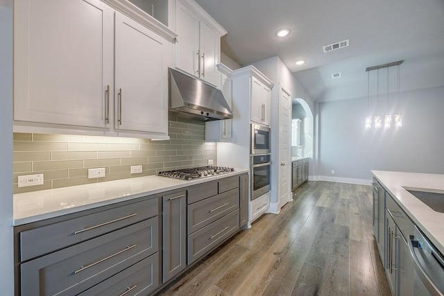 kitchen featuring appliances with stainless steel finishes, white cabinetry, hanging light fixtures, gray cabinetry, and light hardwood / wood-style flooring