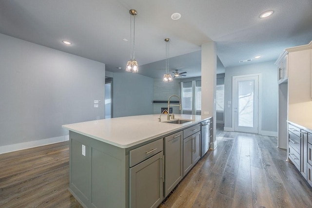 kitchen with a kitchen island with sink, sink, dark wood-type flooring, pendant lighting, and gray cabinets