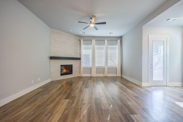 unfurnished living room featuring ceiling fan, a tile fireplace, and hardwood / wood-style floors