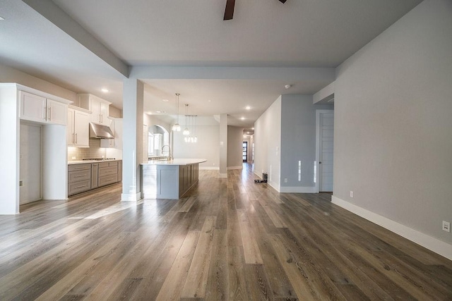 unfurnished living room featuring sink, ceiling fan, and dark wood-type flooring