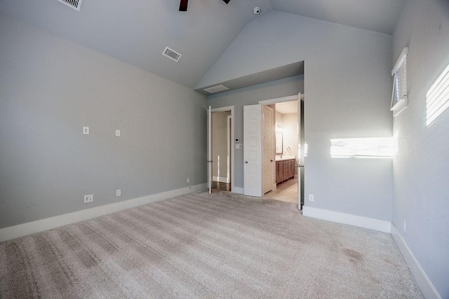 interior space featuring ceiling fan, ensuite bathroom, light colored carpet, and high vaulted ceiling