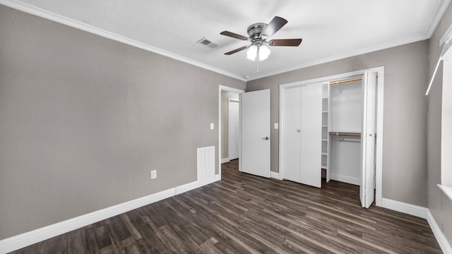 unfurnished bedroom featuring ceiling fan, crown molding, dark hardwood / wood-style floors, and a closet