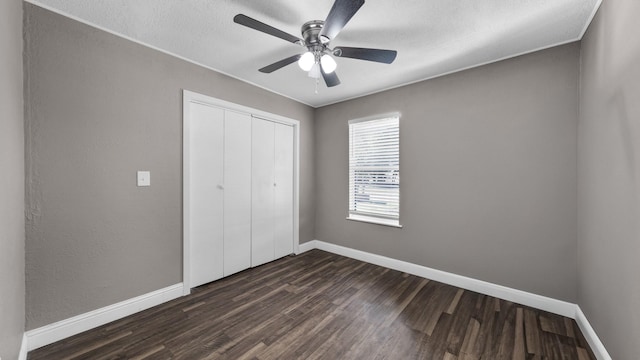 unfurnished bedroom featuring ceiling fan, a closet, a textured ceiling, and dark hardwood / wood-style flooring