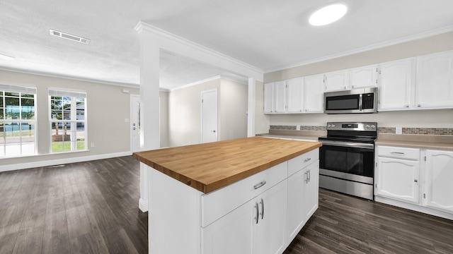 kitchen with white cabinetry, appliances with stainless steel finishes, crown molding, and butcher block counters