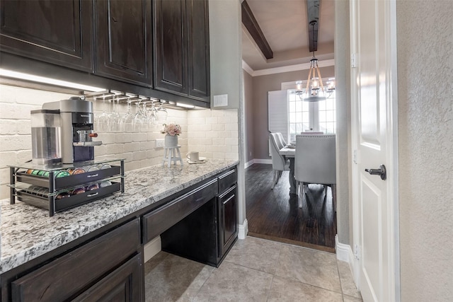 kitchen with dark brown cabinets, hanging light fixtures, light stone countertops, ornamental molding, and beamed ceiling