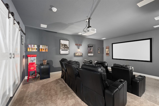 cinema with a textured ceiling, light carpet, and a barn door