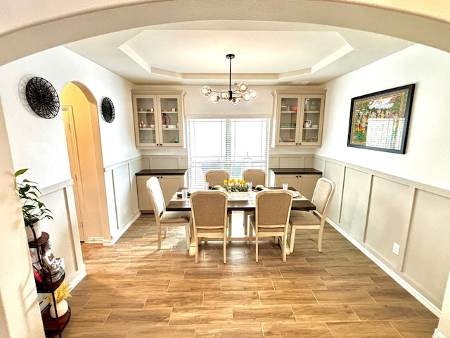 dining area featuring a raised ceiling and a notable chandelier