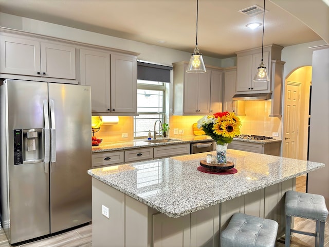 kitchen featuring pendant lighting, appliances with stainless steel finishes, sink, and light stone counters