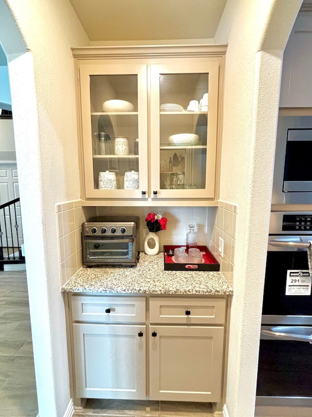 bar with light stone counters, stainless steel appliances, and decorative backsplash