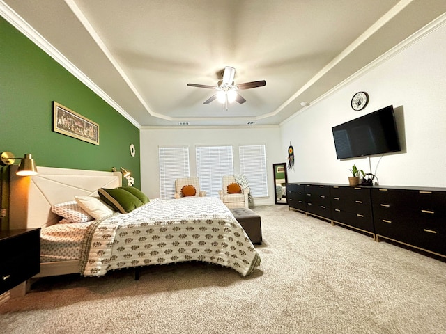 carpeted bedroom with ornamental molding, ceiling fan, and a tray ceiling