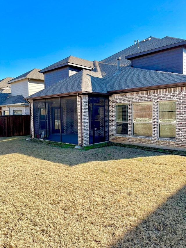 rear view of house featuring a yard and a sunroom