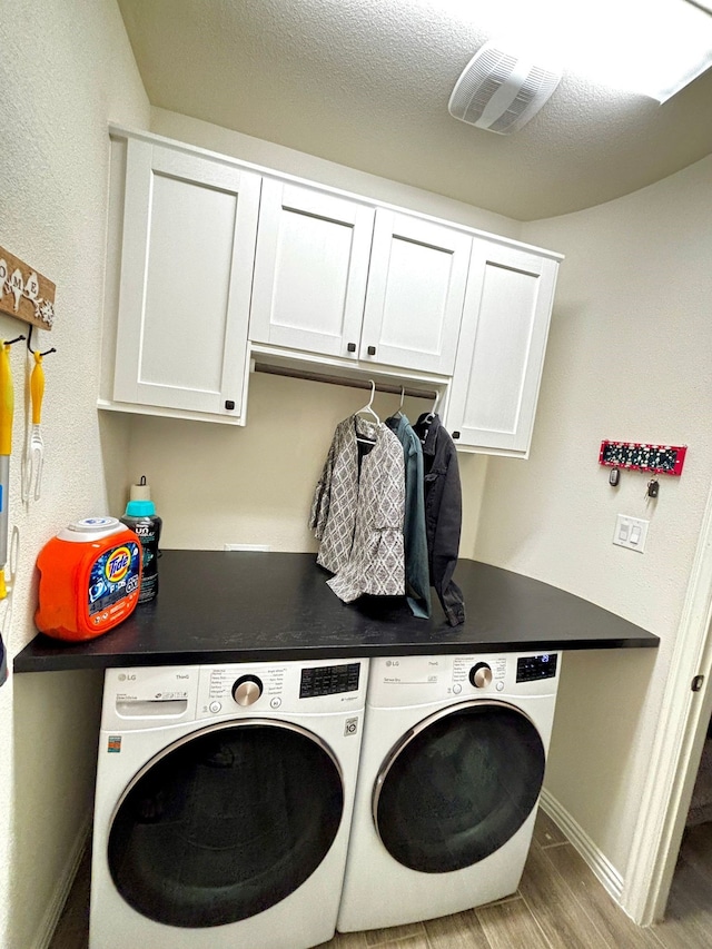 laundry area featuring cabinets, light hardwood / wood-style floors, washer and dryer, and a textured ceiling