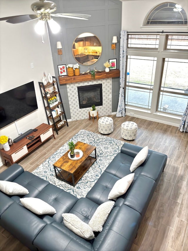 living room with a tile fireplace and ceiling fan