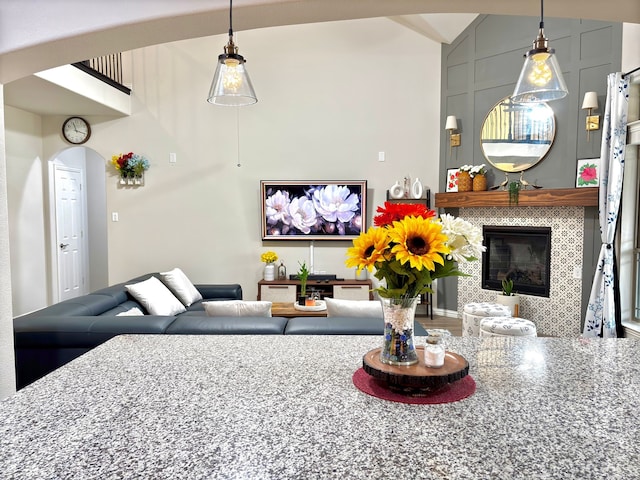 living room featuring high vaulted ceiling and a tile fireplace