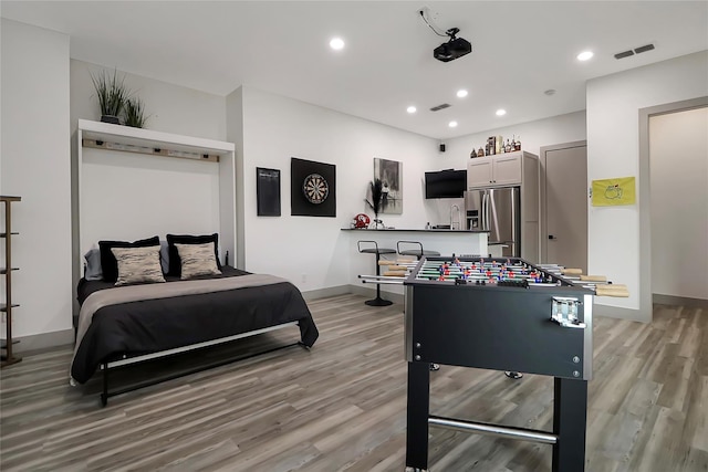 bedroom with light hardwood / wood-style floors and stainless steel fridge