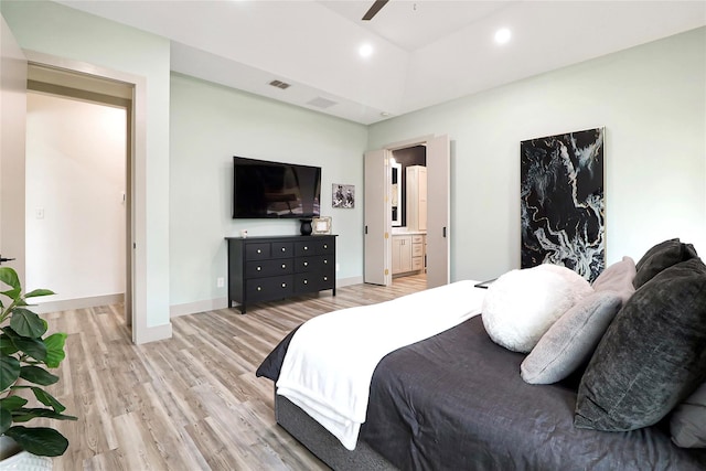 bedroom featuring light wood-type flooring, ceiling fan, and connected bathroom