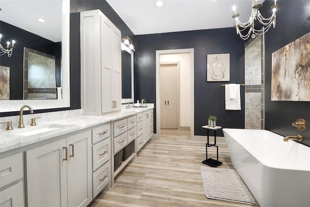 bathroom with hardwood / wood-style floors, vanity, a bathing tub, and an inviting chandelier