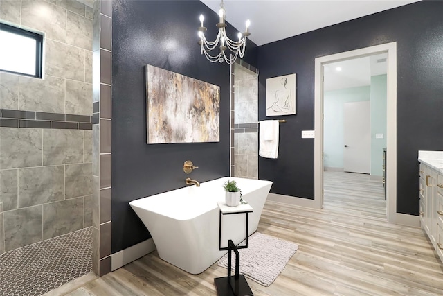 bathroom with a notable chandelier, hardwood / wood-style floors, separate shower and tub, and vanity