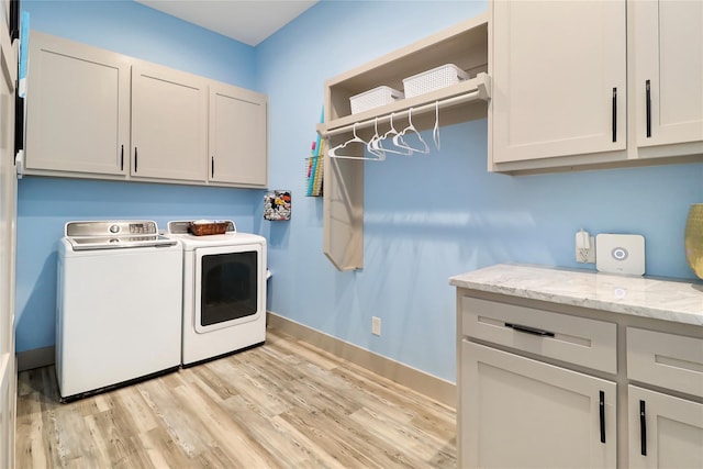 washroom with cabinets, washer and clothes dryer, and light hardwood / wood-style floors