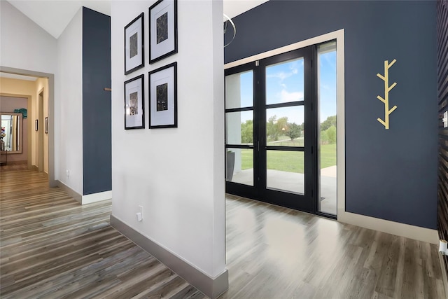 foyer featuring dark wood-type flooring, vaulted ceiling, and french doors