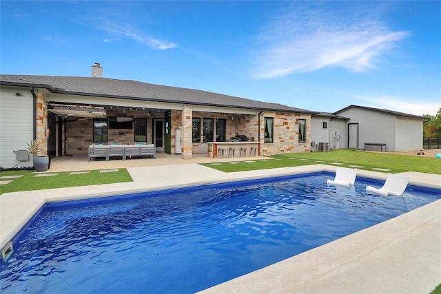 view of pool with a bar, a patio, a yard, an outdoor hangout area, and central air condition unit