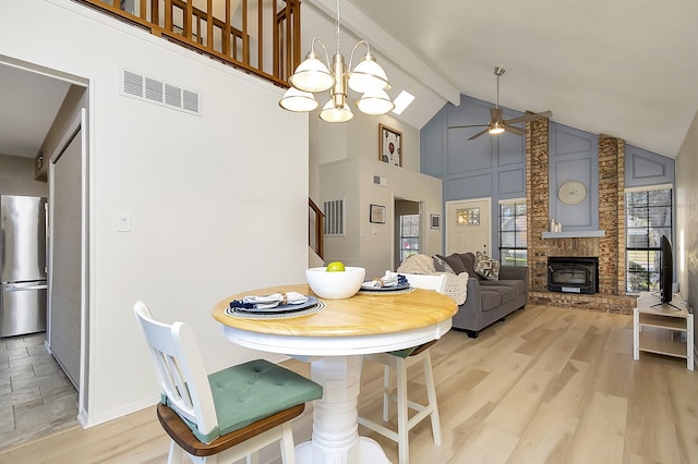 dining room with light wood-type flooring, ceiling fan with notable chandelier, beamed ceiling, and high vaulted ceiling