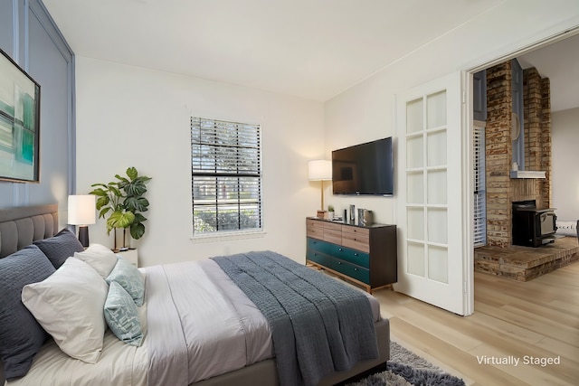 bedroom with light hardwood / wood-style flooring and a wood stove