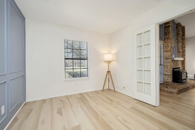 unfurnished room with a wood stove and light hardwood / wood-style floors