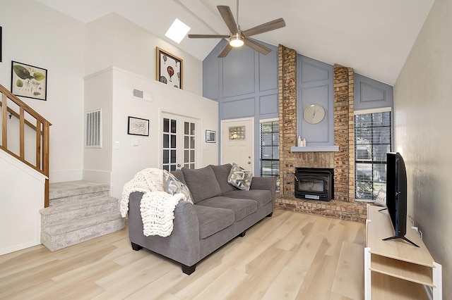 living room with a brick fireplace, french doors, high vaulted ceiling, light hardwood / wood-style flooring, and ceiling fan