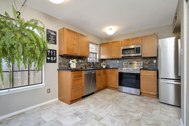 kitchen with appliances with stainless steel finishes, dark countertops, backsplash, and baseboards