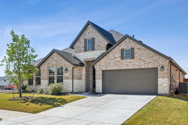 view of front facade with a garage, a front yard, and central AC