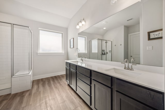 bathroom featuring wood-type flooring, a tile shower, lofted ceiling, and vanity