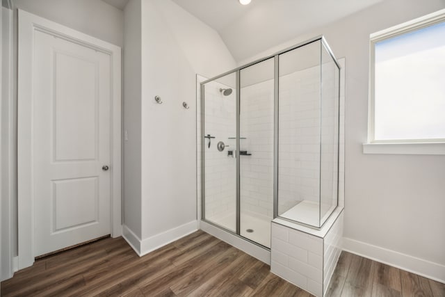 bathroom with a shower with shower door, hardwood / wood-style floors, and lofted ceiling