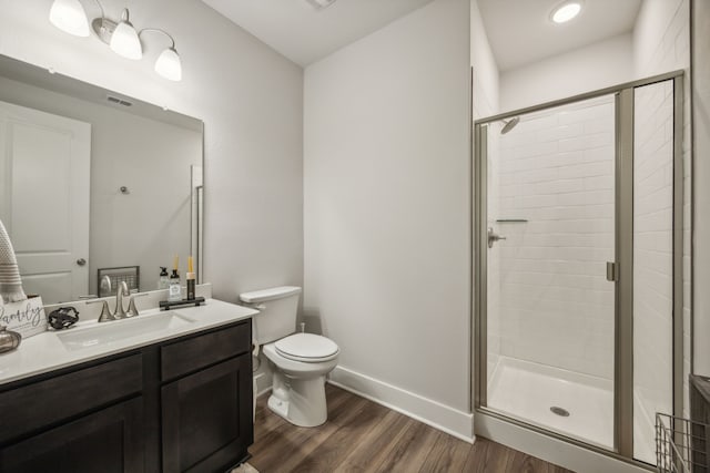 bathroom featuring vanity, hardwood / wood-style flooring, walk in shower, and toilet