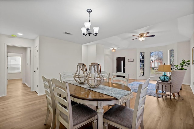 dining space with ceiling fan with notable chandelier and light hardwood / wood-style floors