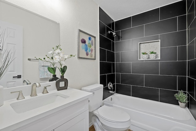 full bathroom featuring tiled shower / bath, vanity, and toilet