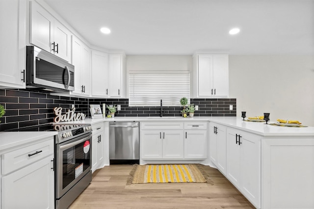 kitchen featuring tasteful backsplash, white cabinets, sink, light hardwood / wood-style flooring, and stainless steel appliances