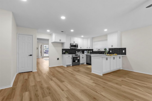 kitchen with white cabinetry, appliances with stainless steel finishes, kitchen peninsula, and tasteful backsplash