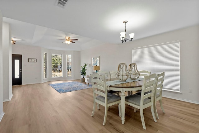 dining area with ceiling fan with notable chandelier and light hardwood / wood-style floors